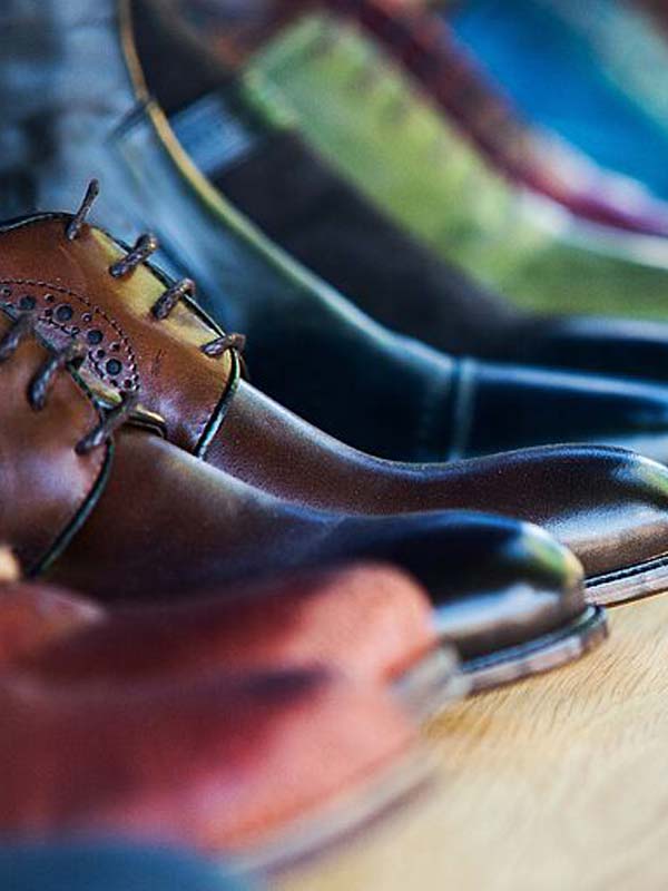 Calzado en piel probado y certificado Zapatos y botas en cuero en varios colores, alineados en un estante